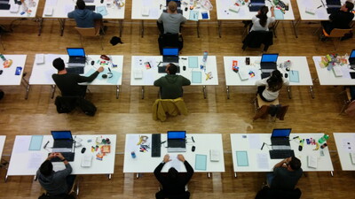 Prüflinge warten auf den gleichzeitigen Start der E-Klausur im Obergericht Bern. Im Vordergrund sind die von IQUL bereitgestellten Prüfungslaptops sowie Maus und Tastatur in einer Full-Service-Prüfung zu sehen.