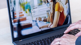 Eine Person tippt auf der Login-Maske der Q-Exam Software, um sich für den gleichzeitigen Start der E-Prüfung anzumelden.