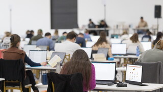 Rechtsreferendarinnen und Rechtsreferendare schreiben das Zweite Staatsexamen in Rheinland-Pfalz am Laptop, daneben ein zweiter Bildschirm mit der digitalen Examensbibliothek