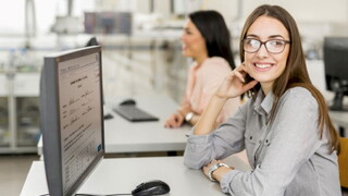 Eine glückliche Studentin blickt auf ihren Laptop, während sie die Prüfungseinsicht mit der Software Q-Exam durchführt.
